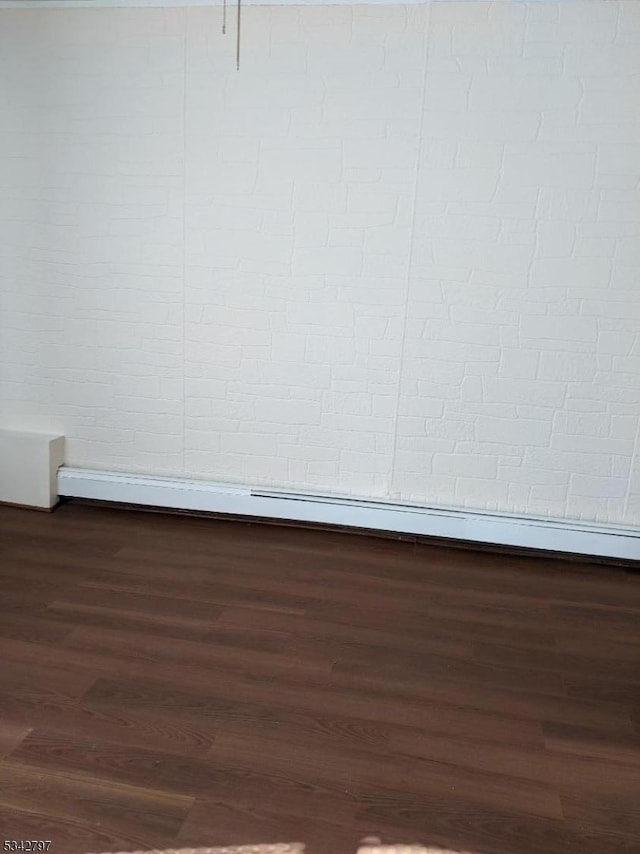 unfurnished room featuring wood finished floors, baseboards, and a baseboard radiator