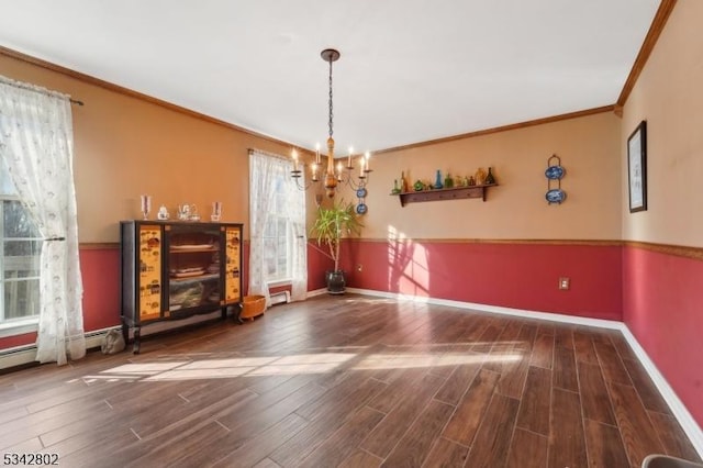 unfurnished dining area featuring a chandelier, baseboards, wood finished floors, and crown molding