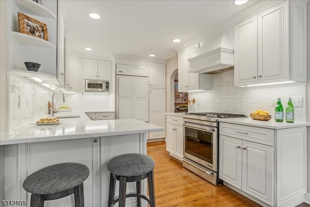 kitchen featuring a sink, appliances with stainless steel finishes, custom exhaust hood, white cabinets, and open shelves