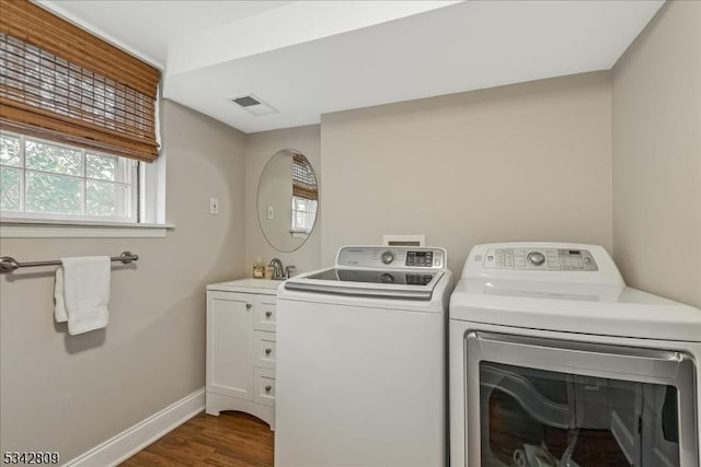 washroom with visible vents, washing machine and dryer, cabinet space, baseboards, and dark wood-style flooring