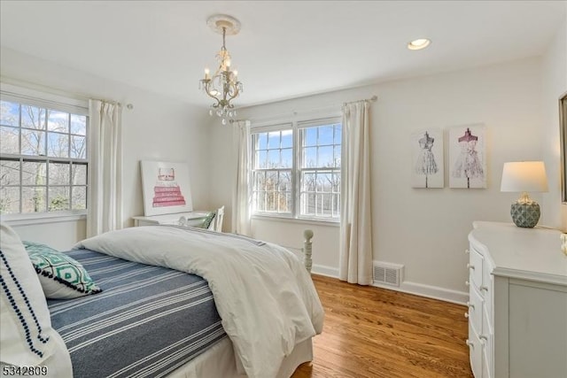 bedroom featuring light wood-style flooring, multiple windows, visible vents, and baseboards