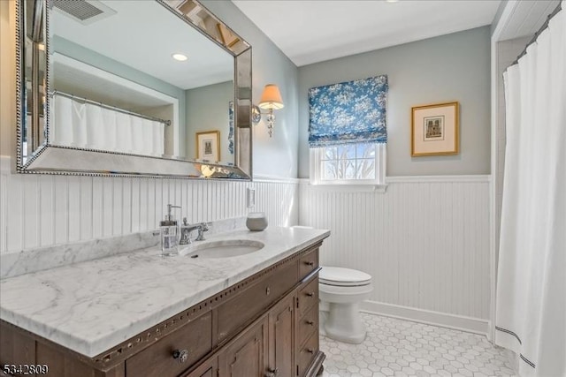 bathroom featuring tile patterned floors, visible vents, toilet, wainscoting, and vanity