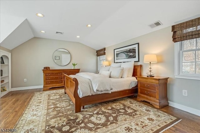 bedroom featuring visible vents, wood finished floors, and vaulted ceiling