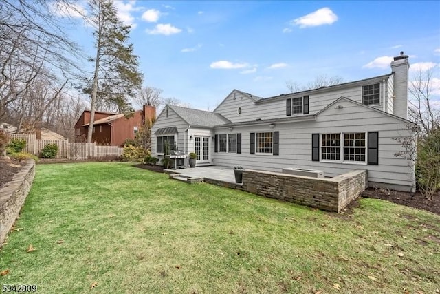 rear view of house featuring a patio area, fence, a lawn, and a chimney