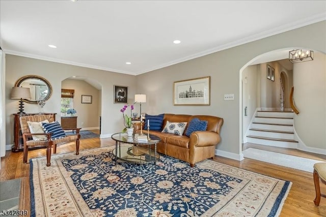 living room with arched walkways, crown molding, baseboards, and wood finished floors