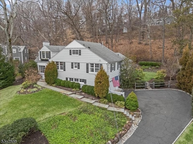 view of front of home with aphalt driveway, a chimney, and a front yard