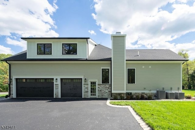 28 Old Forge Dr, Warren Twp, NJ 07059 - rear view of property featuring asphalt driveway, a garage, a chimney, cooling unit, and a yard