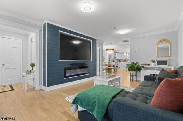 living area featuring visible vents, ornamental molding, a large fireplace, light wood-style floors, and baseboards