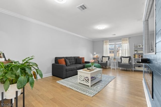 living room featuring baseboards, visible vents, light wood-style flooring, a fireplace, and ornamental molding