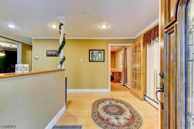 interior space with light wood-type flooring, a baseboard radiator, baseboards, and crown molding