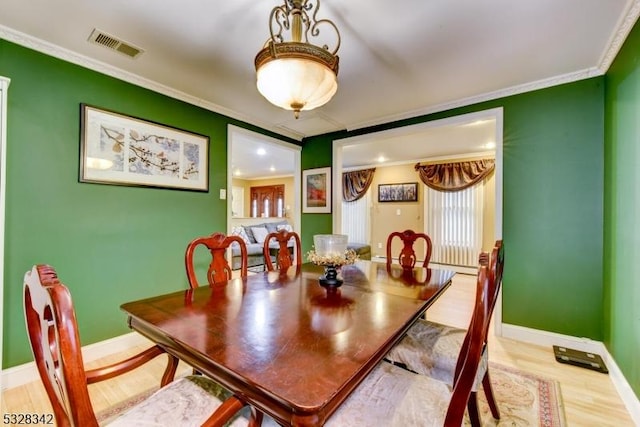 dining room featuring baseboards, visible vents, crown molding, and wood finished floors