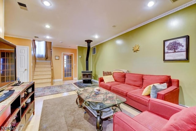 living room with stairs, ornamental molding, wood finished floors, and a wood stove