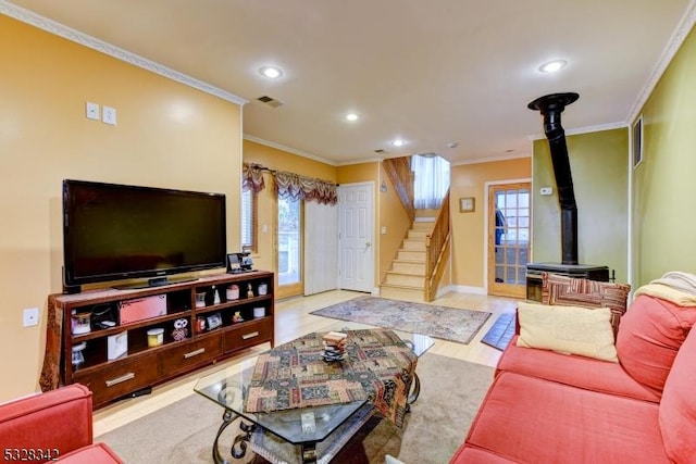 living room featuring stairs, ornamental molding, visible vents, and a wood stove