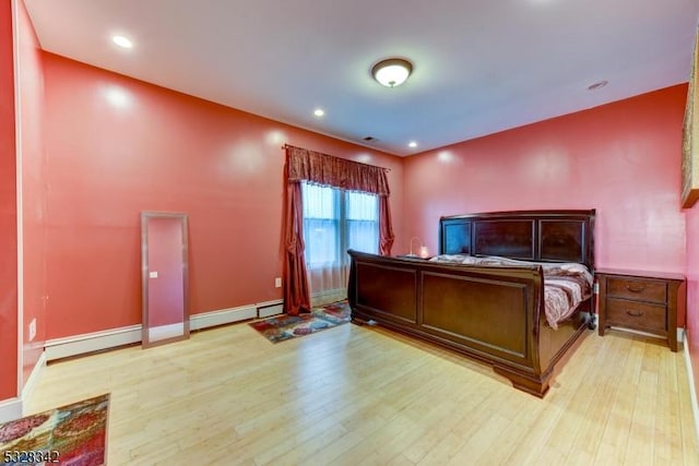 bedroom with a baseboard heating unit, wood finished floors, and recessed lighting