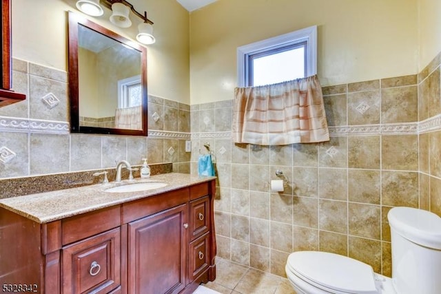 bathroom with a wealth of natural light, tile walls, toilet, and vanity