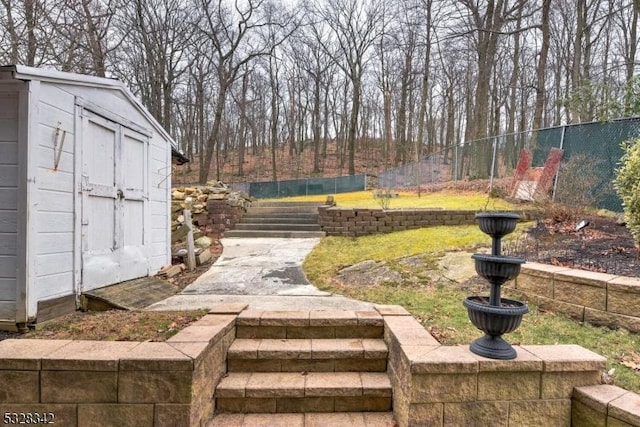 view of yard featuring a storage unit, fence, and an outbuilding