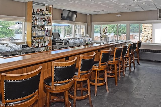 bar featuring radiator, indoor wet bar, and a drop ceiling