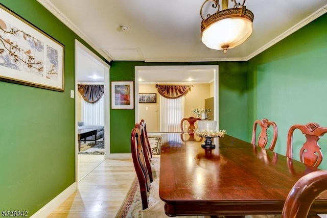 dining area featuring baseboards, wood finished floors, and crown molding