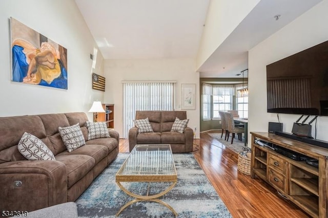 living area with baseboards, high vaulted ceiling, and wood finished floors