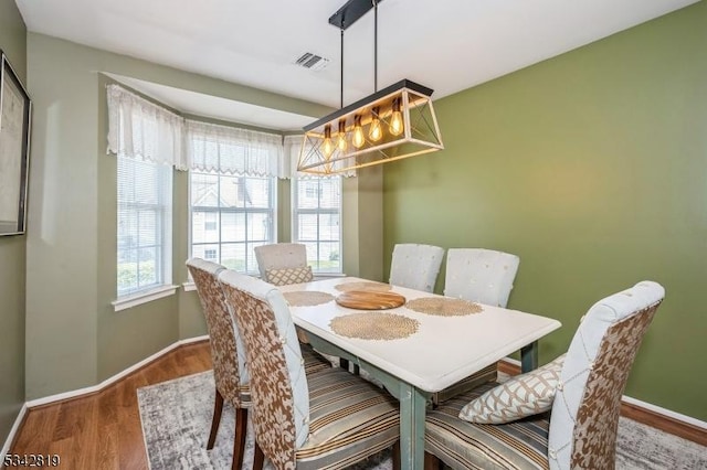 dining area with visible vents, baseboards, and wood finished floors