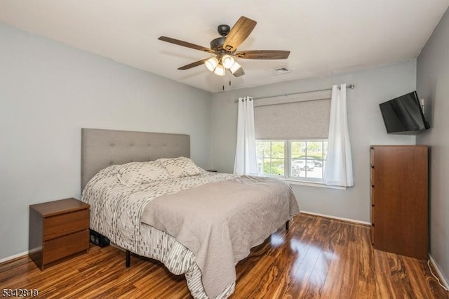 bedroom featuring ceiling fan, visible vents, baseboards, and wood finished floors