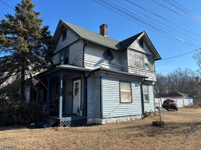 view of side of home featuring a chimney and a yard