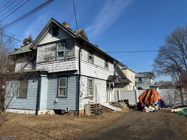 exterior space featuring a chimney and fence