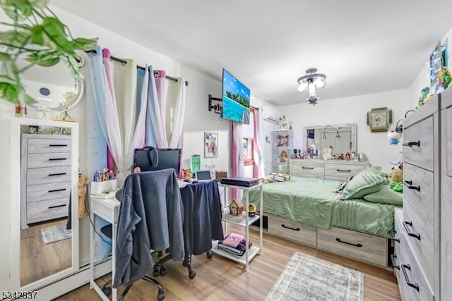 bedroom featuring a baseboard radiator, a wall mounted AC, and wood finished floors