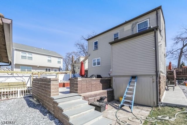 back of house featuring stairway and fence