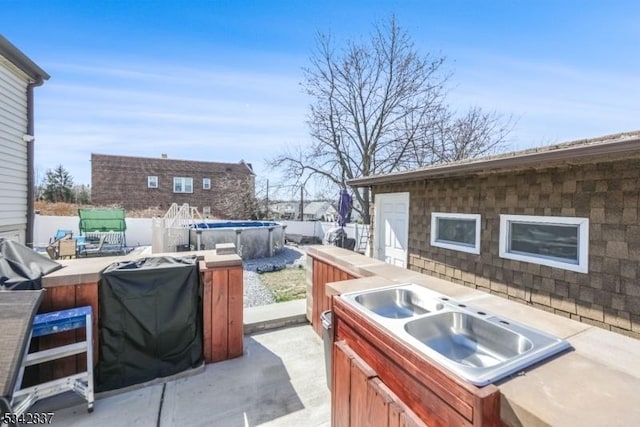 view of patio with area for grilling, fence, and a sink