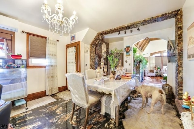 dining area with plenty of natural light, a notable chandelier, wood finished floors, and arched walkways