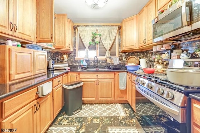 kitchen with dark countertops, backsplash, stainless steel appliances, and a sink