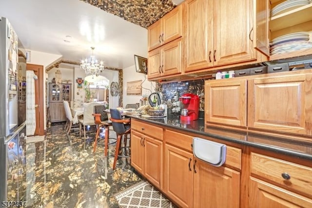 kitchen featuring an inviting chandelier, dark countertops, and backsplash