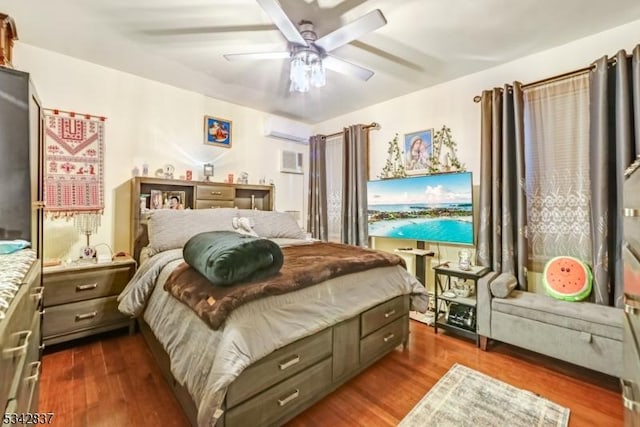 bedroom featuring dark wood-type flooring, a wall unit AC, and a ceiling fan