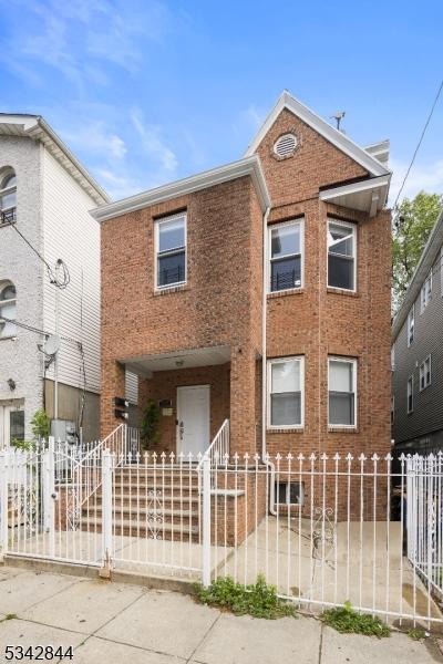 townhome / multi-family property featuring a fenced front yard and brick siding