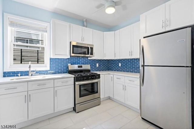 kitchen with a sink, tasteful backsplash, white cabinetry, stainless steel appliances, and light countertops