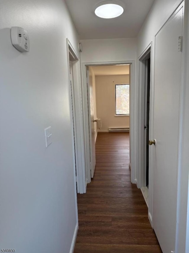 hall with baseboard heating, dark wood-type flooring, and baseboards