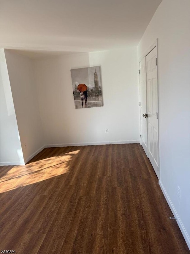 spare room featuring wood finished floors and baseboards