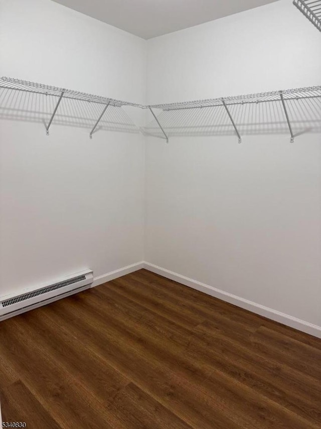 spacious closet featuring dark wood-style flooring and a baseboard radiator