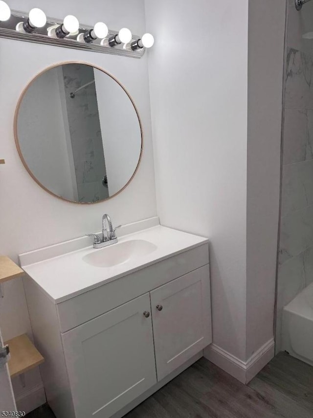 bathroom featuring vanity, wood finished floors, baseboards, a shower, and a bath