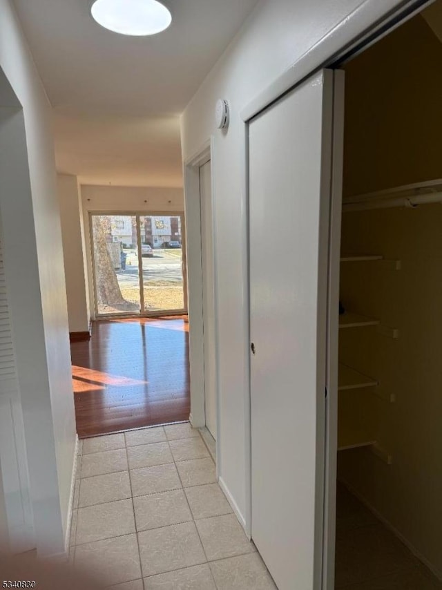 corridor featuring light tile patterned floors and baseboards