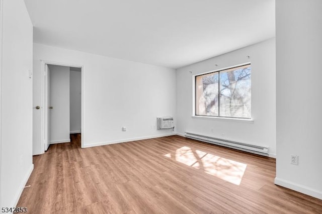 spare room with a baseboard heating unit, baseboards, an AC wall unit, and wood finished floors