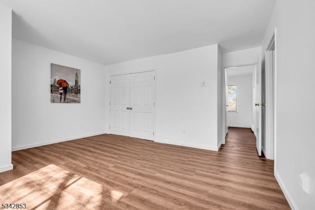 unfurnished bedroom with a closet, baseboards, and wood finished floors