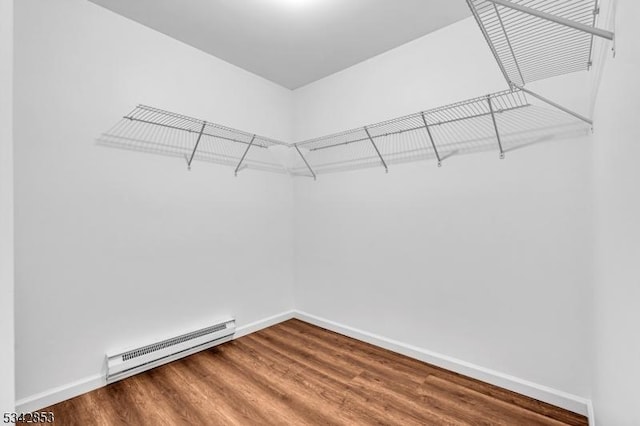 walk in closet with a baseboard heating unit and wood finished floors