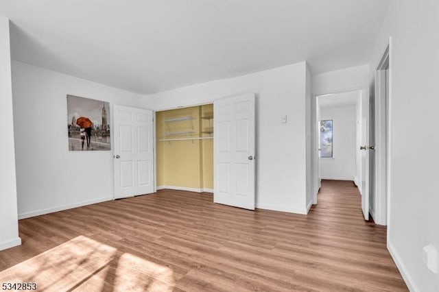 unfurnished bedroom featuring a closet, baseboards, and light wood finished floors