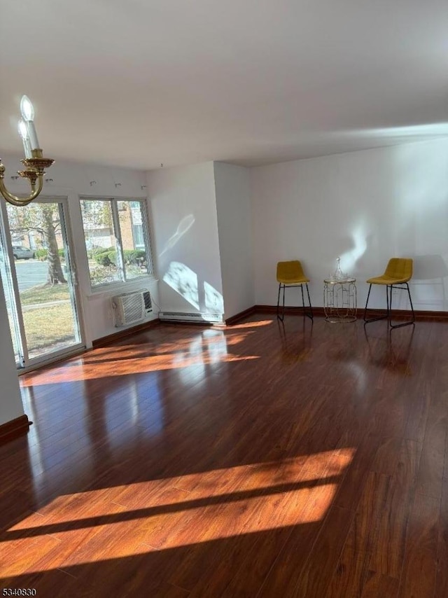 interior space featuring a chandelier, baseboards, wood finished floors, and a wall unit AC