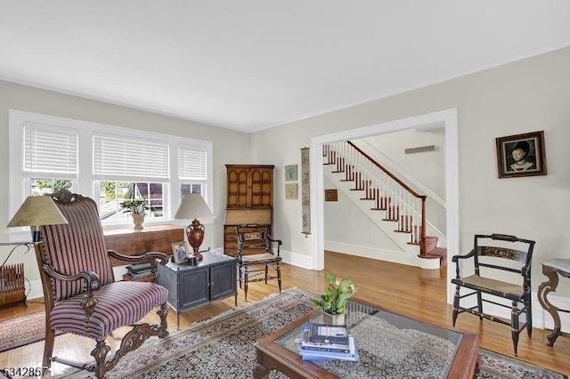 living room featuring stairs, wood finished floors, baseboards, and a desk