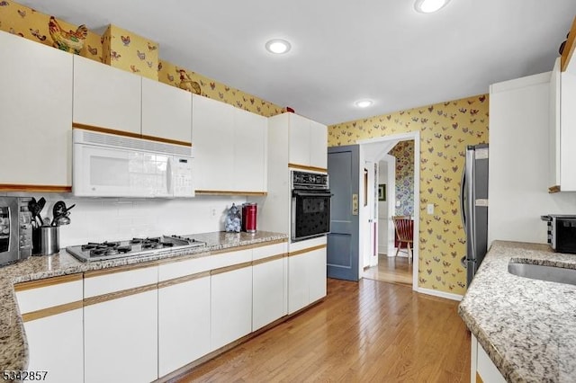 kitchen featuring appliances with stainless steel finishes, wallpapered walls, light wood-type flooring, recessed lighting, and baseboards