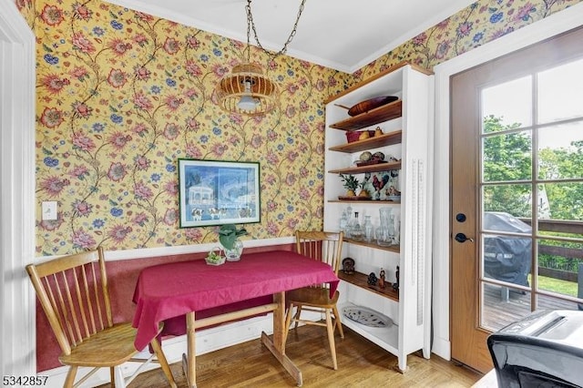 dining room with wallpapered walls, crown molding, and wood finished floors
