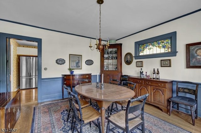 dining space with wood finished floors, ornamental molding, and a chandelier
